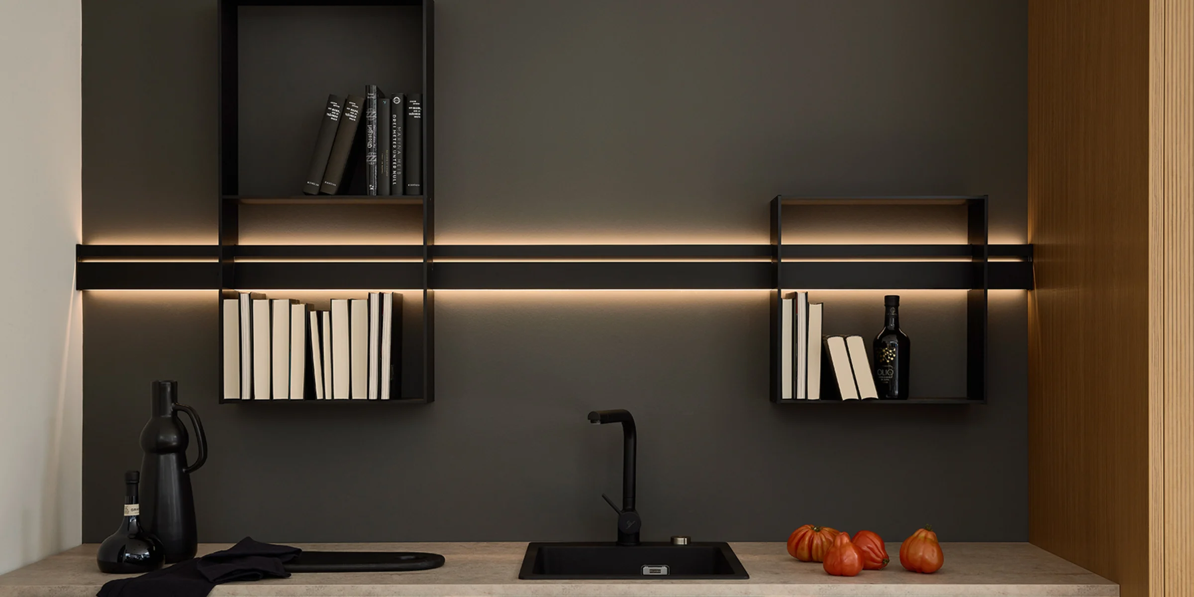 Cucina moderna con scaffali scuri e illuminazione sopra il piano di lavoro di Nolte Kitchen.