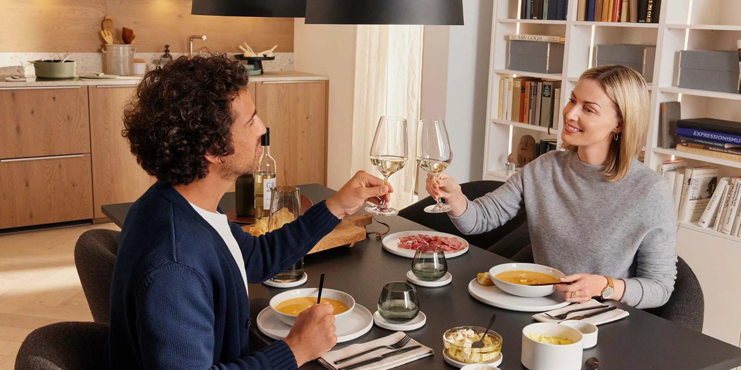 Coppia che brinda con calici di vino in una cucina moderna. Nolte Kitchen.