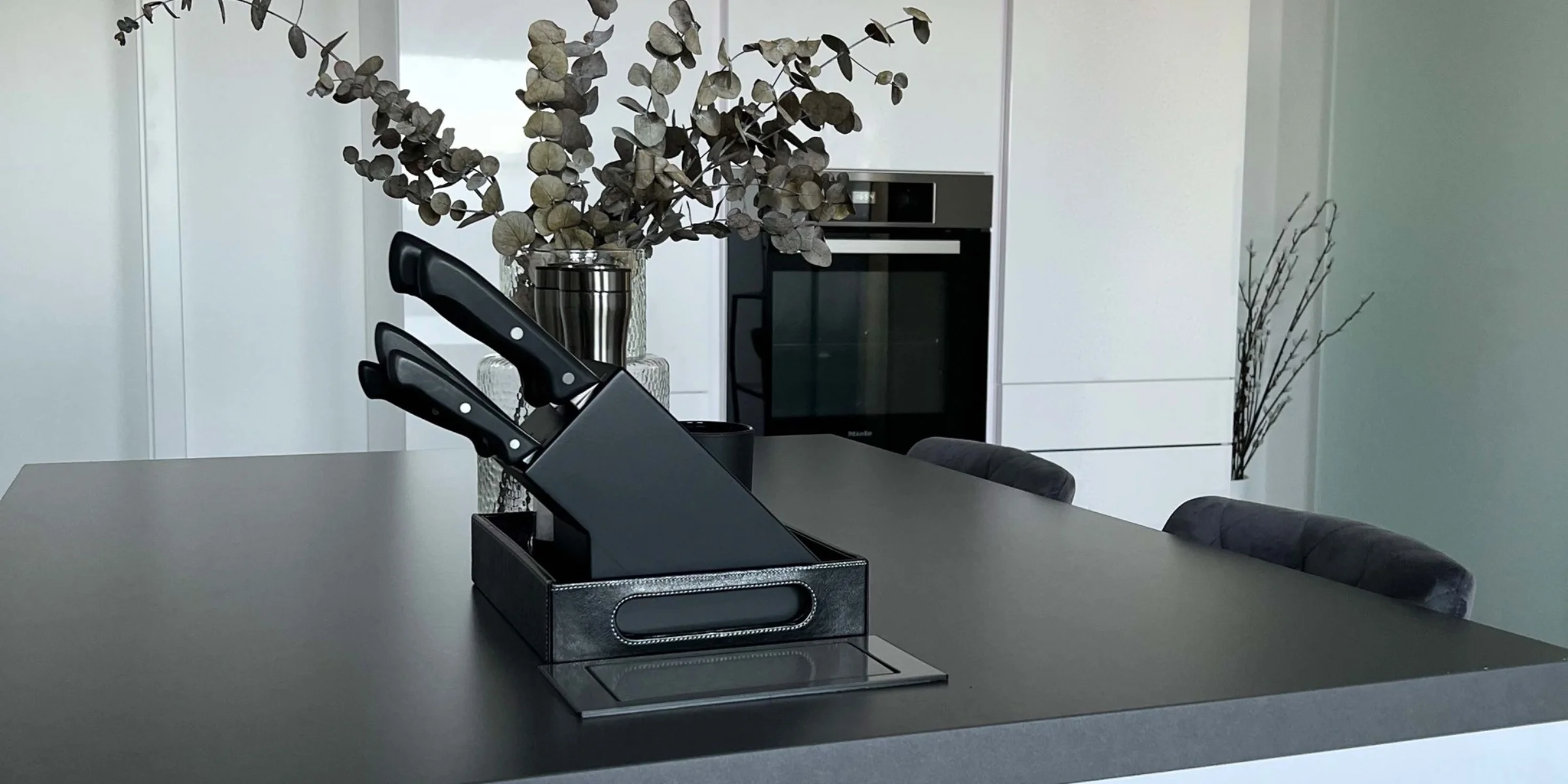 Cucina moderna con isola e armadi bianchi, decorata con piante. Nolte Kitchen.