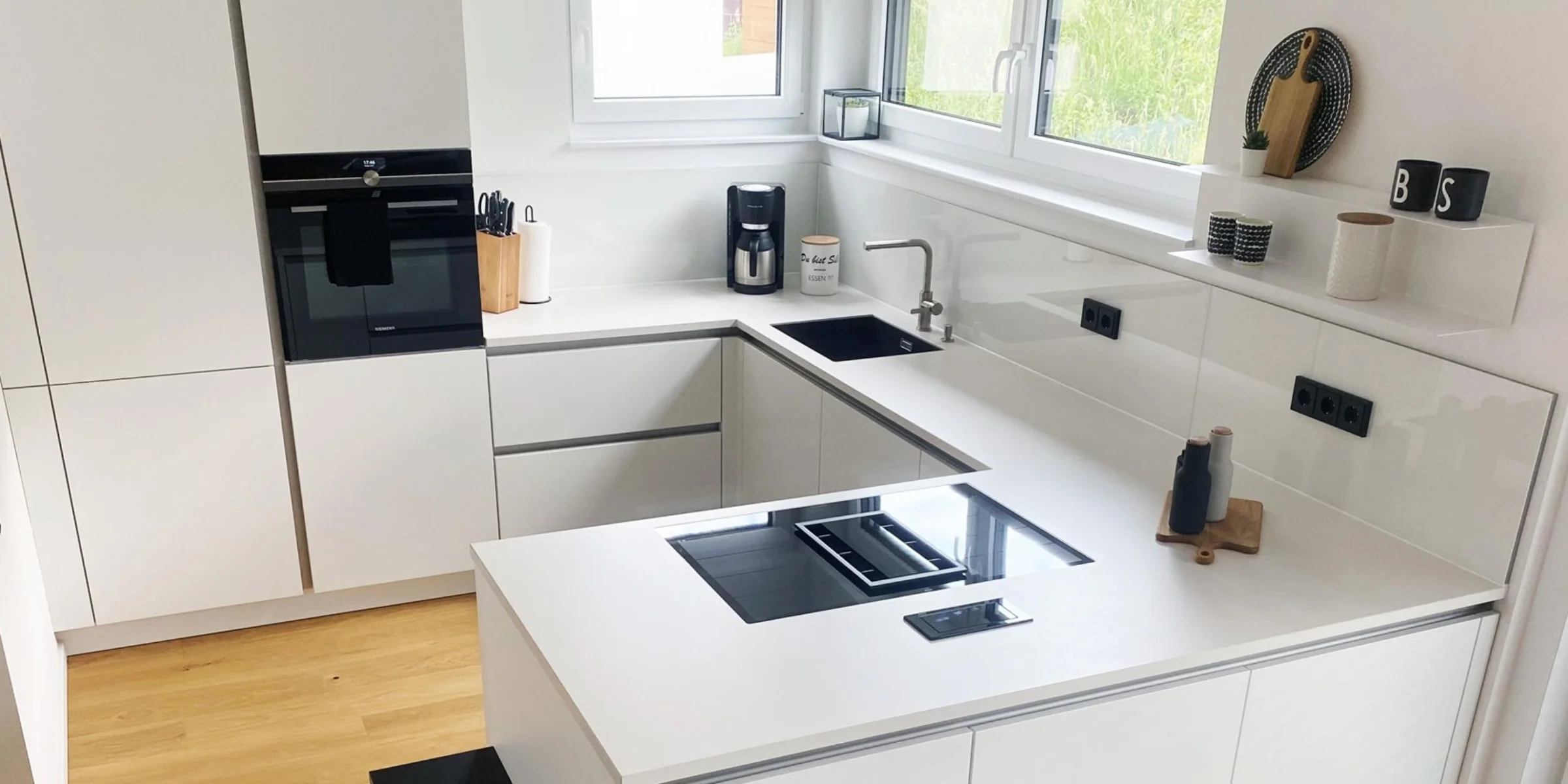 Cucina moderna bianca con elettrodomestici integrati e lavello angolare, design di Nolte Kitchen.