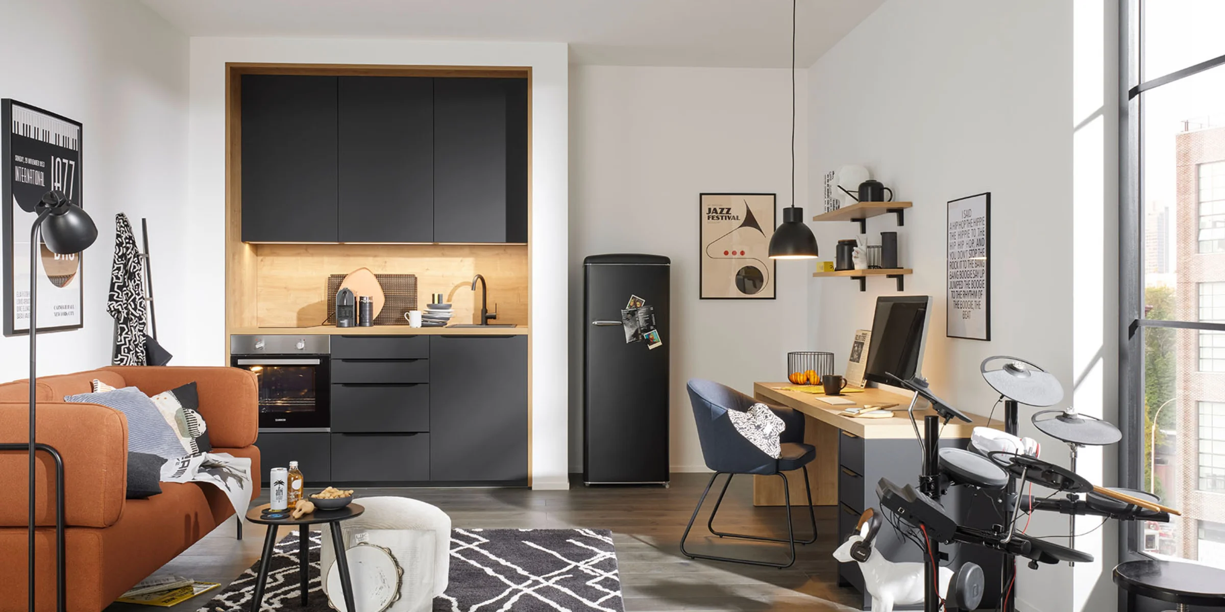 In una stanza moderna con cucina grigia di Nolte Kitchen, ci sono un divano, una scrivania e una batteria elettronica.