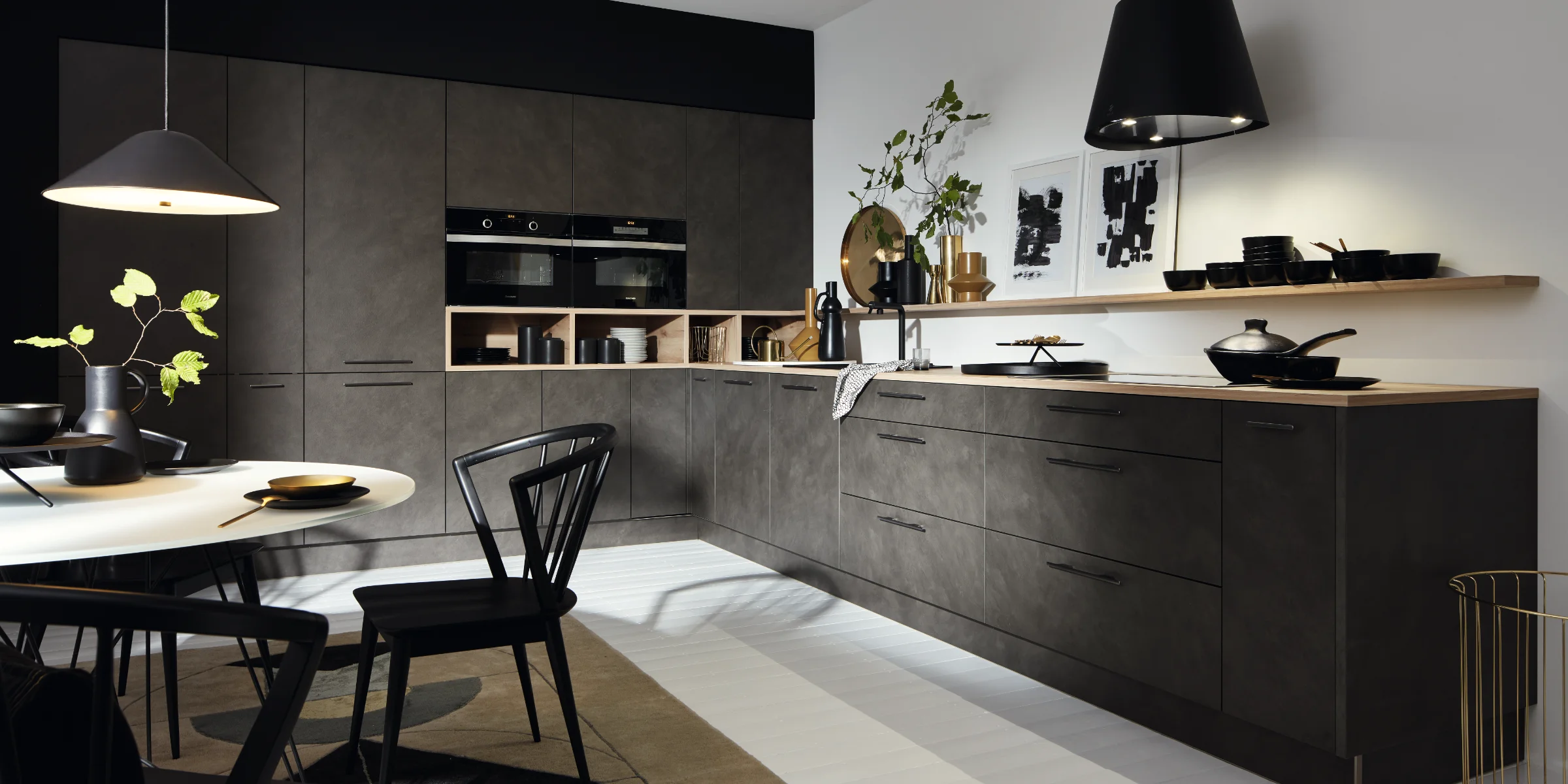 Cucina moderna con armadi scuri, tavolo da pranzo e decorazioni, progettata da Nolte Kitchen.