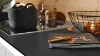 Cucina moderna con piano nero e accenti in rame, design di Nolte Kitchen.