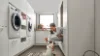 Una donna gioca con un cane in una moderna lavanderia di Nolte Utility Rooms.