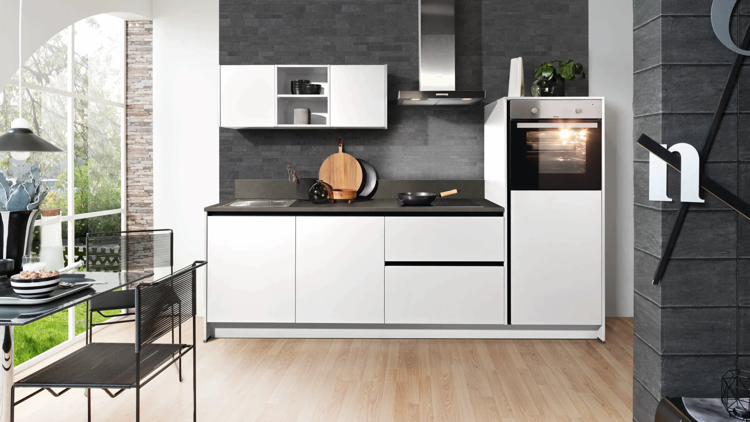 Cuisine moderne blanche avec mur sombre et four intégré. Express Küchen.