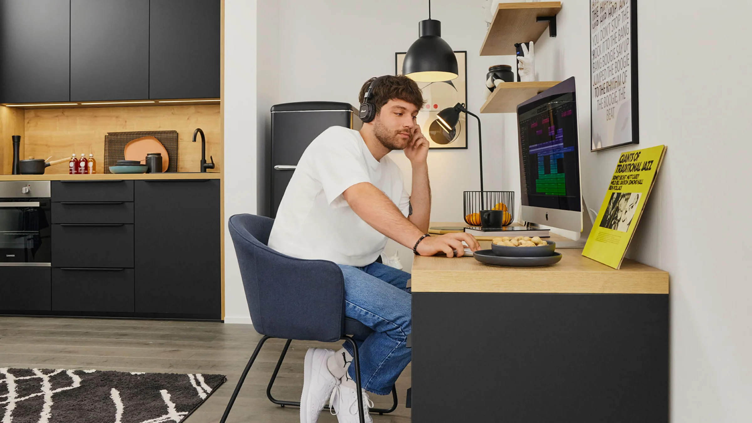 Un uomo lavora in una cucina moderna di Nolte Kitchen, seduto alla scrivania con un computer.