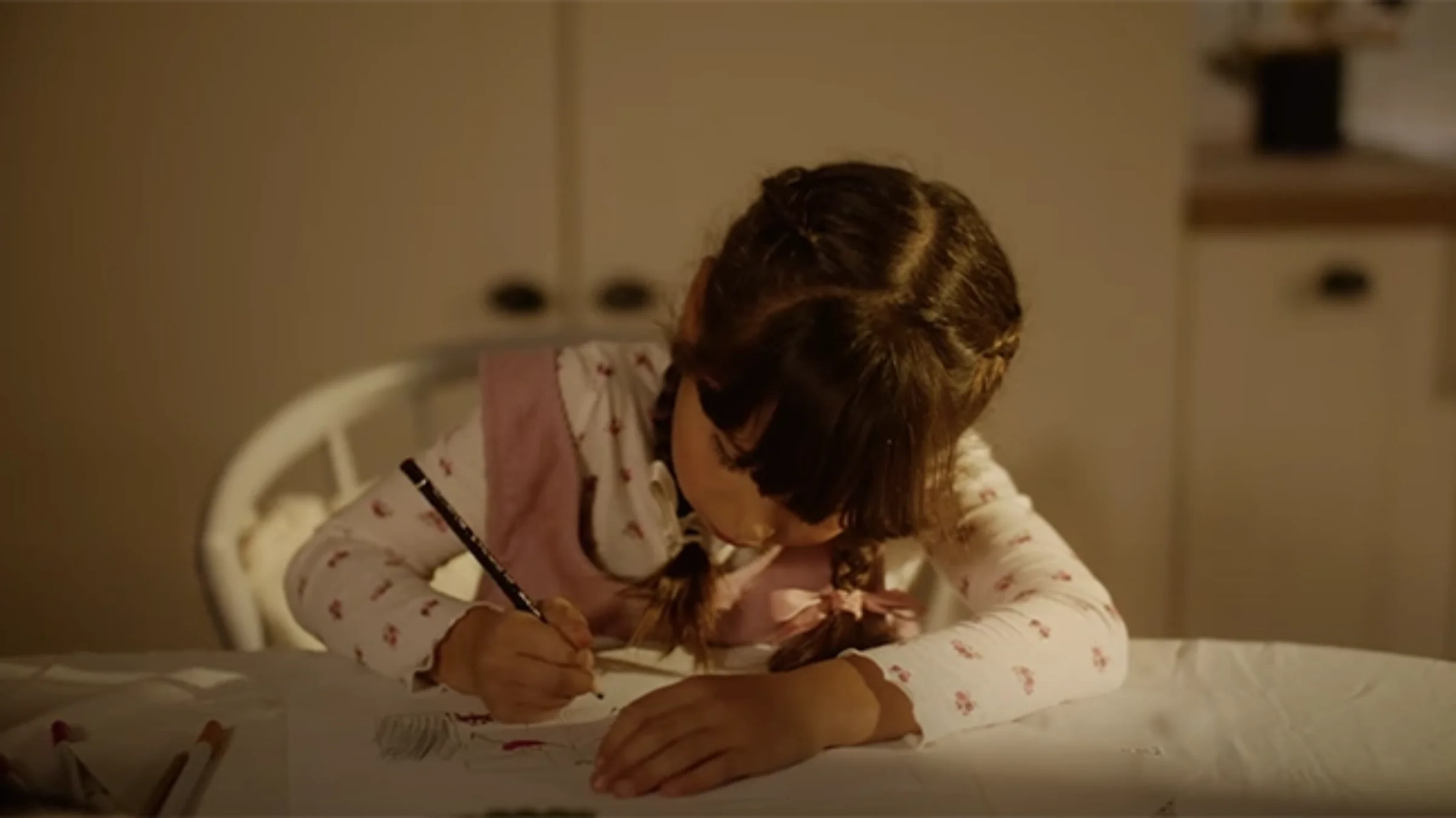 Un bambino disegna concentrato a un tavolo in un ambiente accogliente.