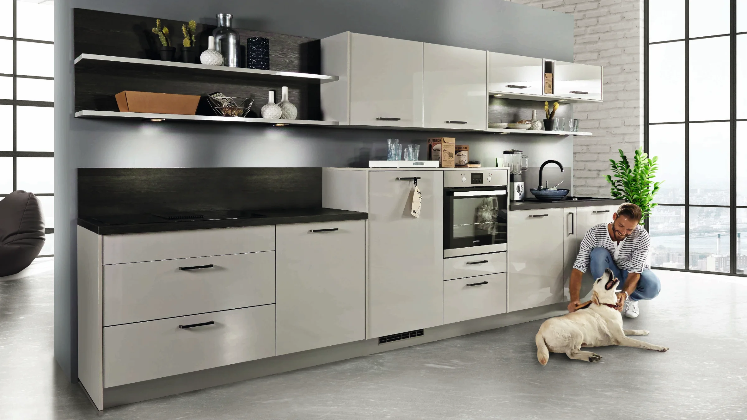 Dans une cuisine moderne, une personne joue avec un chien. Express Küchen.