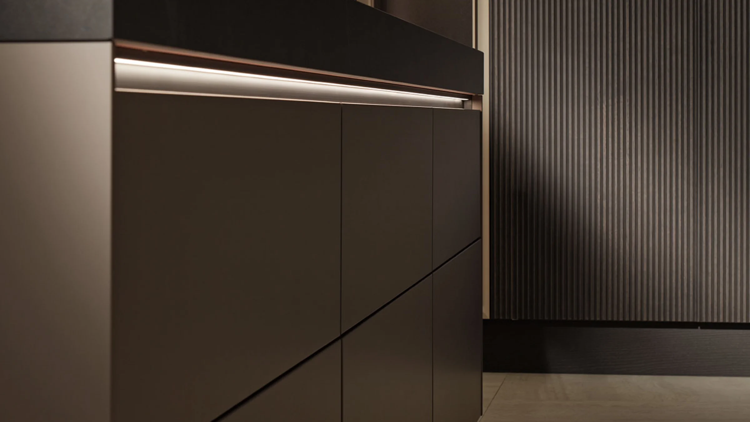 Cucina moderna con eleganti armadi scuri e illuminazione di Nolte Kitchen.