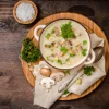 Piatto di zuppa di funghi con prezzemolo e funghi freschi su un tavolo di legno.