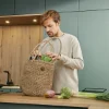 Un uomo in una cucina moderna di Nolte Kitchen sistema la spesa su un piano di lavoro.