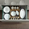 Cassetto da cucina aperto con stoviglie e divisori in legno, Nolte Kitchen.