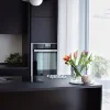 Cucina moderna con piano nero e fiori colorati, design di Nolte Kitchen.