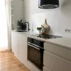 Cucina moderna con armadi bianchi e pavimento in legno di Nolte Kitchen.
