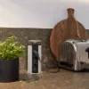 Cucina moderna con tostapane e piante aromatiche sul piano di lavoro, presentata da Nolte Kitchen.