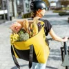 Persona con una grande borsa gialla piena di cibo spinge una bicicletta.