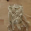 Bicchiere con decorazione macramè su tavolo di legno.