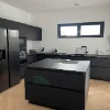 Cucina moderna con isola nera e elettrodomestici, progettata da Nolte Kitchen.