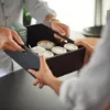 Due persone si scambiano una scatola nera con cosmetici in un elegante Nolte SPA.