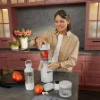 Una donna prepara un frullato in una cucina moderna con armadi rossi. Nolte Kitchen.