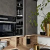 Cucina moderna con armadi grigi e dettagli in legno, decorata con piante. Nolte Kitchen.