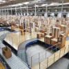 Un grande magazzino pieno di scatole e nastri trasportatori, collegato a Nolte Kitchen.