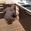 Una persona lavora in una cucina moderna con armadi scuri. Nolte Kitchen.