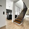 Cucina moderna con parete nera e isola, accanto una scala in legno. Nolte Kitchen.