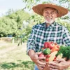 Un uomo con cappello di paglia tiene un cesto di verdure fresche in un campo.