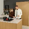 Una coppia guarda un libro di cucina in una cucina moderna con dettagli in legno, Nolte Kitchen.