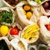 Verdura e frutta fresca in borse di stoffa su un tavolo.