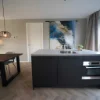 Cucina moderna con isola, tavolo da pranzo e grande vetrata in uno spazio aperto. Nolte Kitchen.