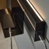 Uno smartphone si carica su uno scaffale con illuminazione integrata; design moderno di Nolte Living.