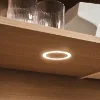 Un placard de cuisine en bois éclairé avec des verres et un bol blanc. Express Küchen.