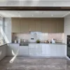 Cucina moderna con armadi grigi e beige, elettrodomestici e pavimento in marmo. Nolte Kitchen.