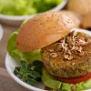 Un burger vegetariano con lattuga e germogli su un piatto.