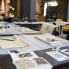 In un elegante spazio, tavoli con materiali creativi e sedie sono disposti, nel contesto di Nolte Living.