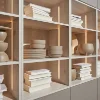Scaffale con ciotole decorative e libri, elegantemente illuminato, parte di Nolte Living.