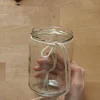 Una mano tiene un bicchiere con una corda intorno su un tavolo di legno.