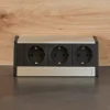 Una ciabatta tripla è integrata in una superficie di legno.