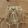 Vaso di vetro con supporto in macramè su un tavolo di legno.