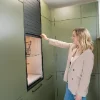 Una donna apre un armadio in una moderna lavanderia progettata da Nolte Utility Rooms.