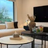 Un elegante soggiorno arredato con tavolini e decorazioni, presentato da Nolte Living.