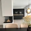 Cucina moderna con arredi neri e camino, in primo piano un tavolo da pranzo. Nolte Kitchen.