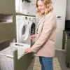 Una donna si trova in una moderna lavanderia con lavatrice e asciugatrice di Nolte Utility Rooms.