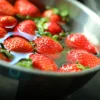 Fragole galleggiano in una ciotola di metallo piena d'acqua.