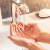 Una persona tiene las manos bajo agua corriente en el baño, Nolte SPA.