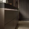 Cucina moderna con eleganti armadi scuri e illuminazione di Nolte Kitchen.