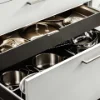 Un armadietto da cucina aperto mostra pentole e padelle dal design moderno di Nolte Kitchen.