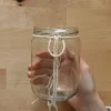 Una mano annoda una corda attorno a un barattolo vuoto.